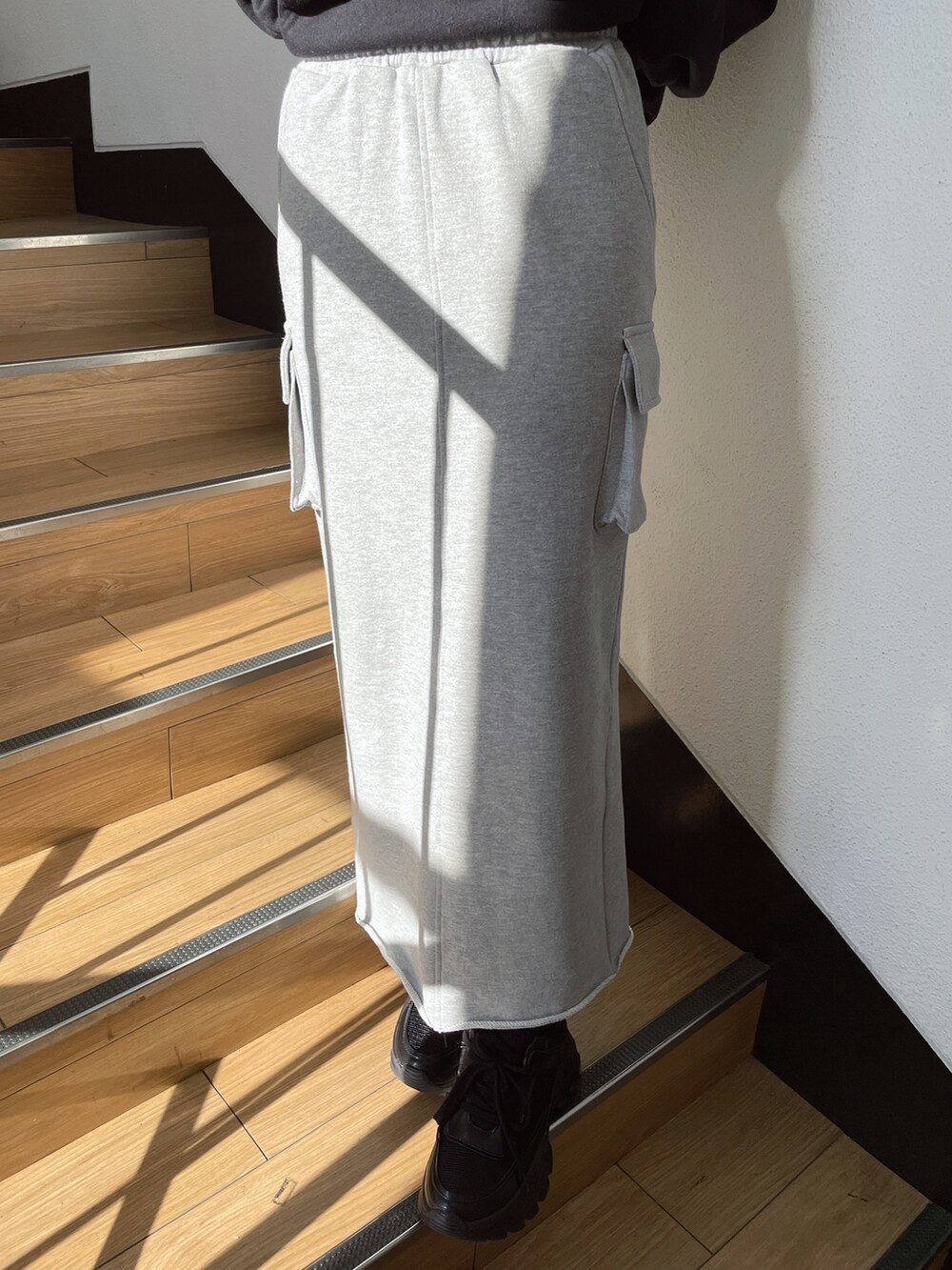 ブラック系のパーカー、グレー系のスカート、ブラック系のスニーカーを着用したレディースの冬コーディネートの5枚目の写真