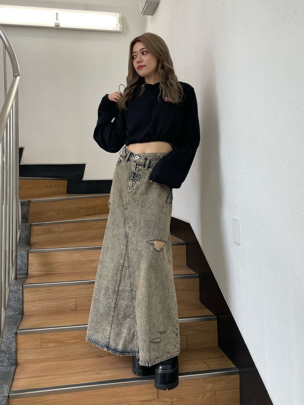 ブラック系のパーカー、ブルー系のデニムスカートを着用したレディースの秋コーディネートの3枚目の写真