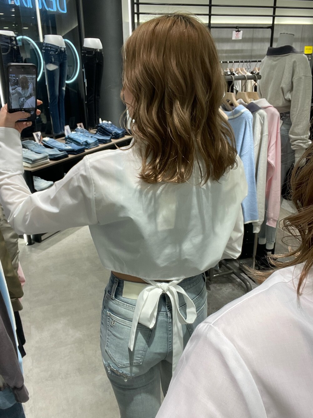ホワイト系のシャツ/ブラウス、ブルー系のデニムパンツ、ホワイト系のパンプスを着用したレディースの冬コーディネートの3枚目の写真