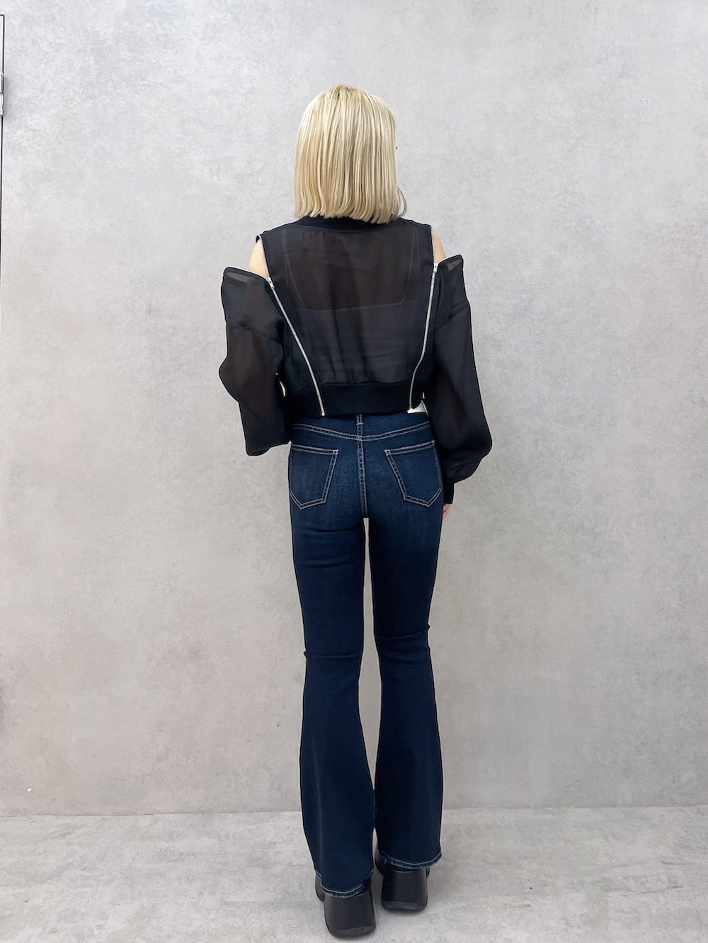 ブルー系のデニムパンツ、ホワイト系のキャミソール、ブラック系のブルゾンを着用したレディースの春コーディネートの3枚目の写真