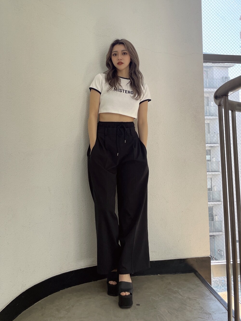 ブラック系のその他パンツ、ブラック系のサンダル、ホワイト系のTシャツ/カットソーを着用したレディースの春コーディネートの2枚目の写真