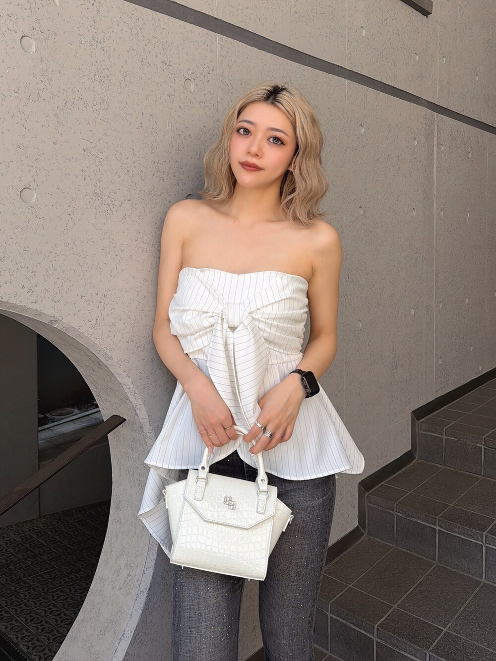 ホワイト系のキャミソール、ブラック系のデニムパンツ、ホワイト系のハンドバッグを着用したレディースの夏コーディネートの4枚目の写真