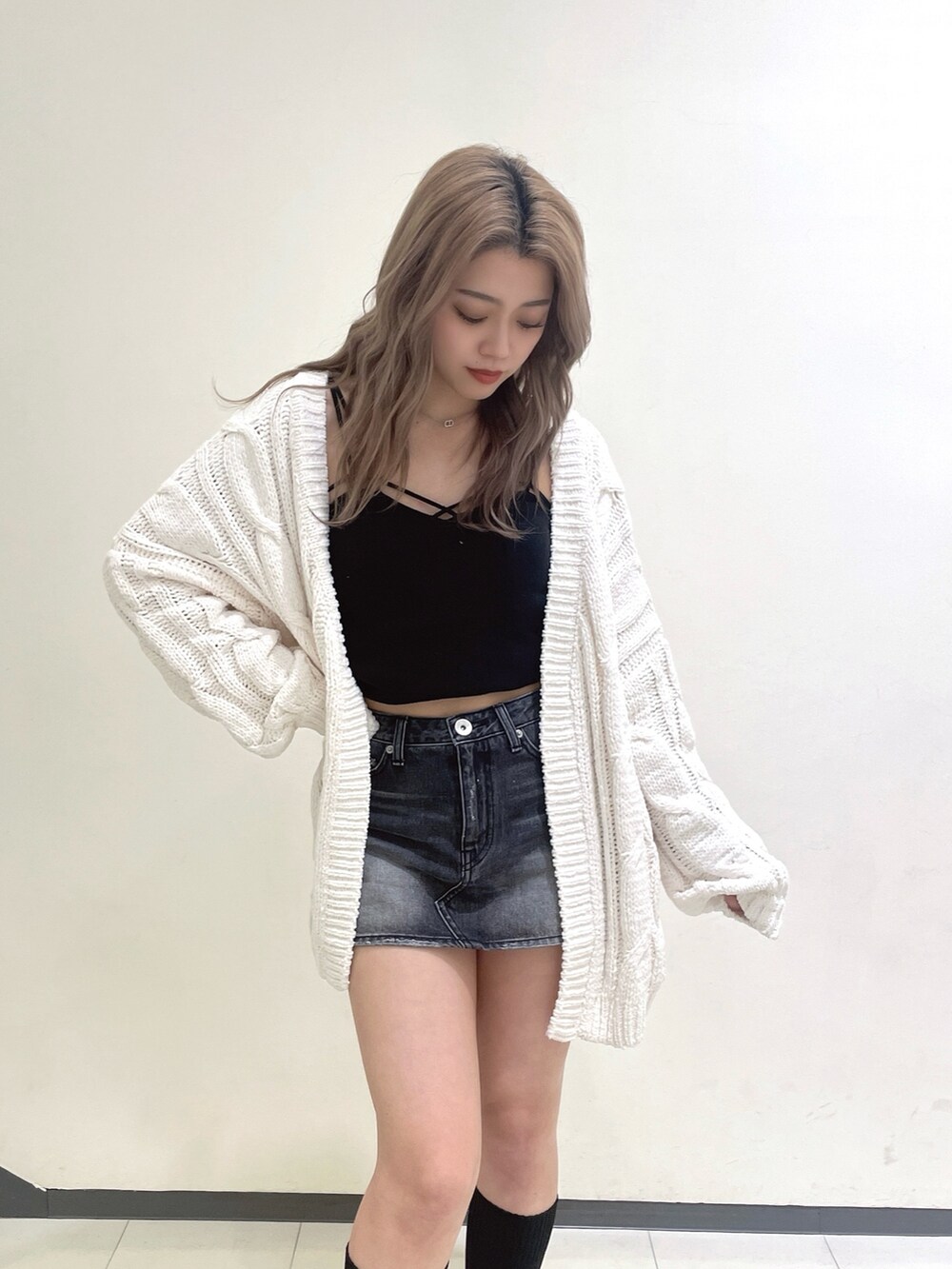 ホワイト系のカーディガン/ボレロ、ブラック系のデニムスカート、ブラック系のブーツを着用したレディースの冬コーディネートの4枚目の写真