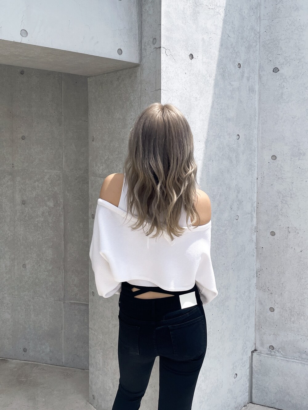 ホワイト系のアンサンブル、ブラック系のデニムパンツ、ブラック系のパンプスを着用したレディースの秋コーディネートの4枚目の写真