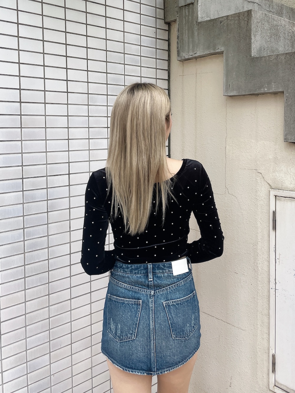 ブラック系のTシャツ/カットソー、ブルー系のデニムスカート、ブラック系のブーツを着用したレディースの秋コーディネートの4枚目の写真