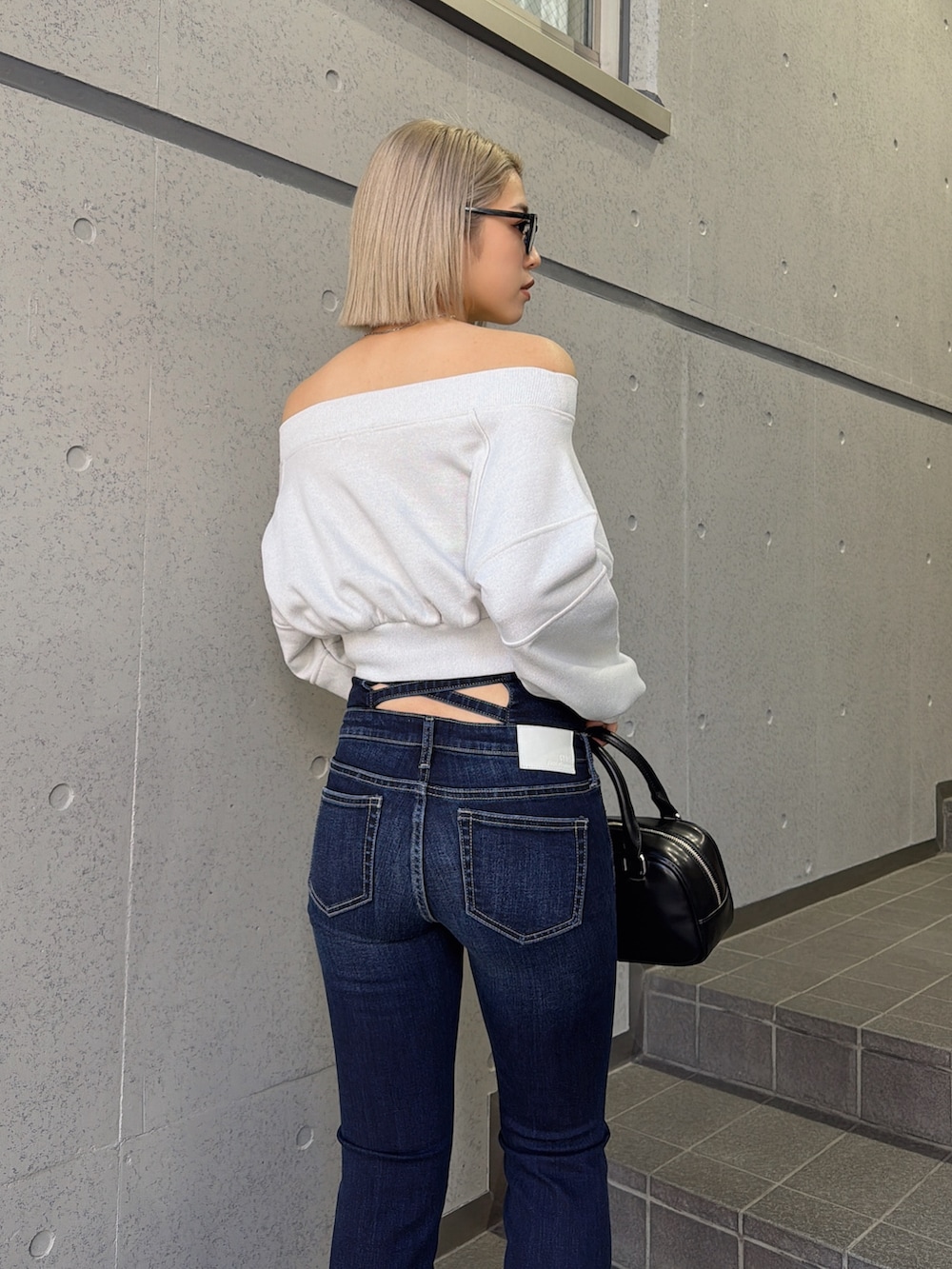 ホワイト系のTシャツ/カットソー、ブルー系のデニムパンツ、ブラック系のハンドバッグを着用したレディースの冬コーディネートの4枚目の写真