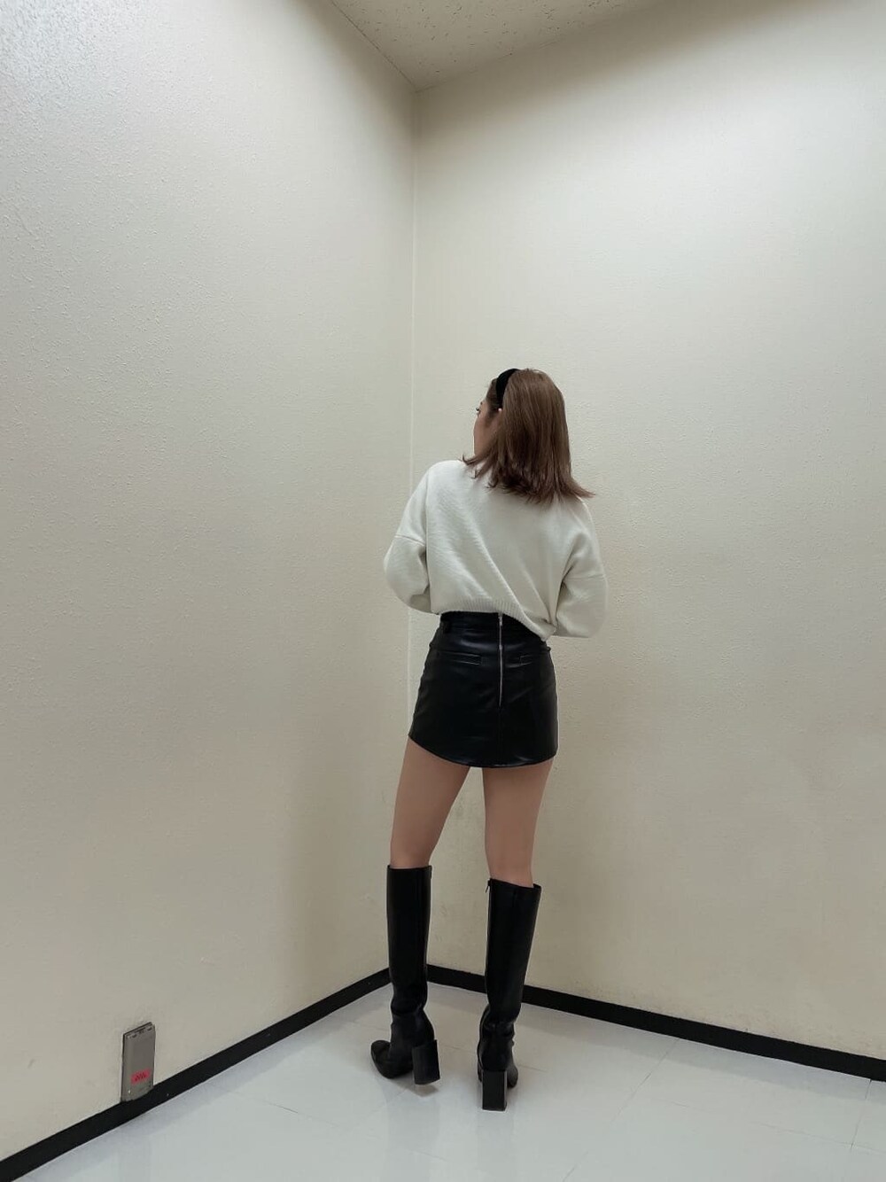 ブラック系のスカート、ブラック系のブーツ、ホワイト系のニット/セーターを着用したレディースの秋コーディネートの2枚目の写真
