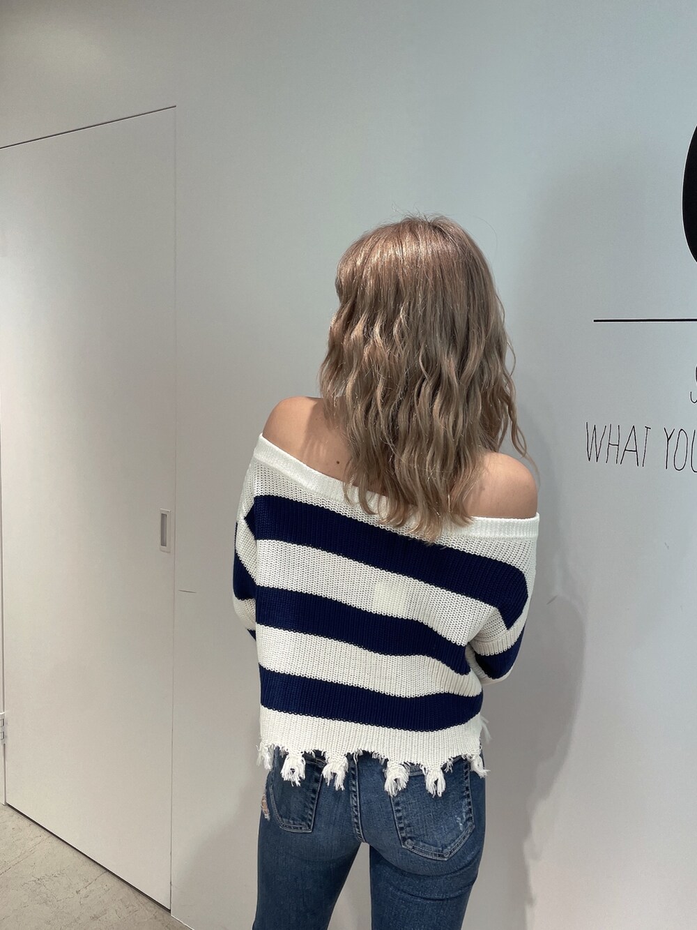 ブルー系のニット/セーター、ブルー系のデニムパンツ、ホワイト系のパンプスを着用したレディースの夏コーディネートの5枚目の写真