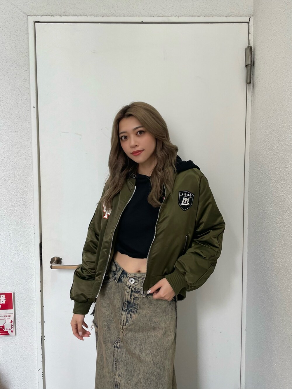 グリーン系のブルゾン、ブルー系のデニムスカート、ブラック系のブーツを着用したレディースの秋コーディネートの5枚目の写真