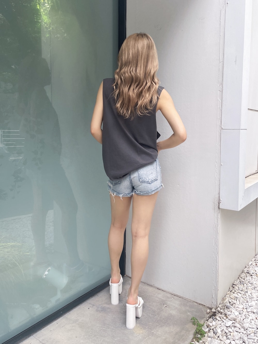 グレー系のタンクトップ、ブルー系のデニムパンツ、ホワイト系のサンダルを着用したレディースの夏コーディネートの2枚目の写真