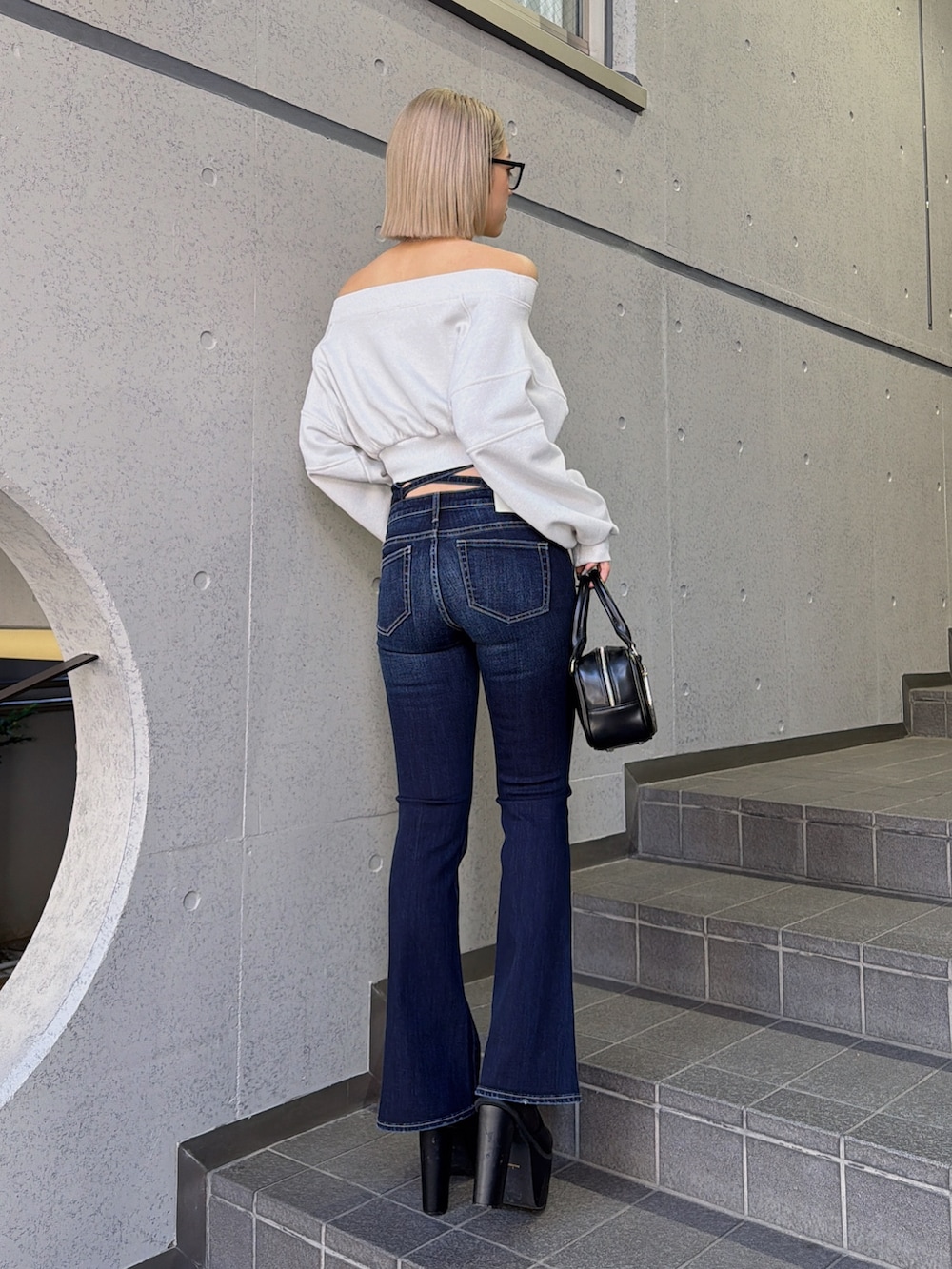 ホワイト系のTシャツ/カットソー、ブルー系のデニムパンツ、ブラック系のハンドバッグを着用したレディースの冬コーディネートの2枚目の写真