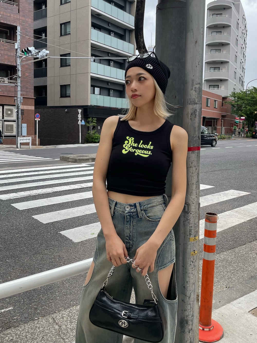 ブラック系のタンクトップ、ブルー系のデニムパンツ、ブラック系のハンドバッグを着用したレディースの春コーディネートの2枚目の写真