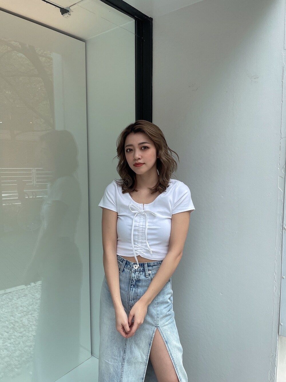 ブルー系のデニムスカート、ホワイト系のTシャツ/カットソー、ホワイト系のパンプスを着用したレディースの春コーディネートの4枚目の写真