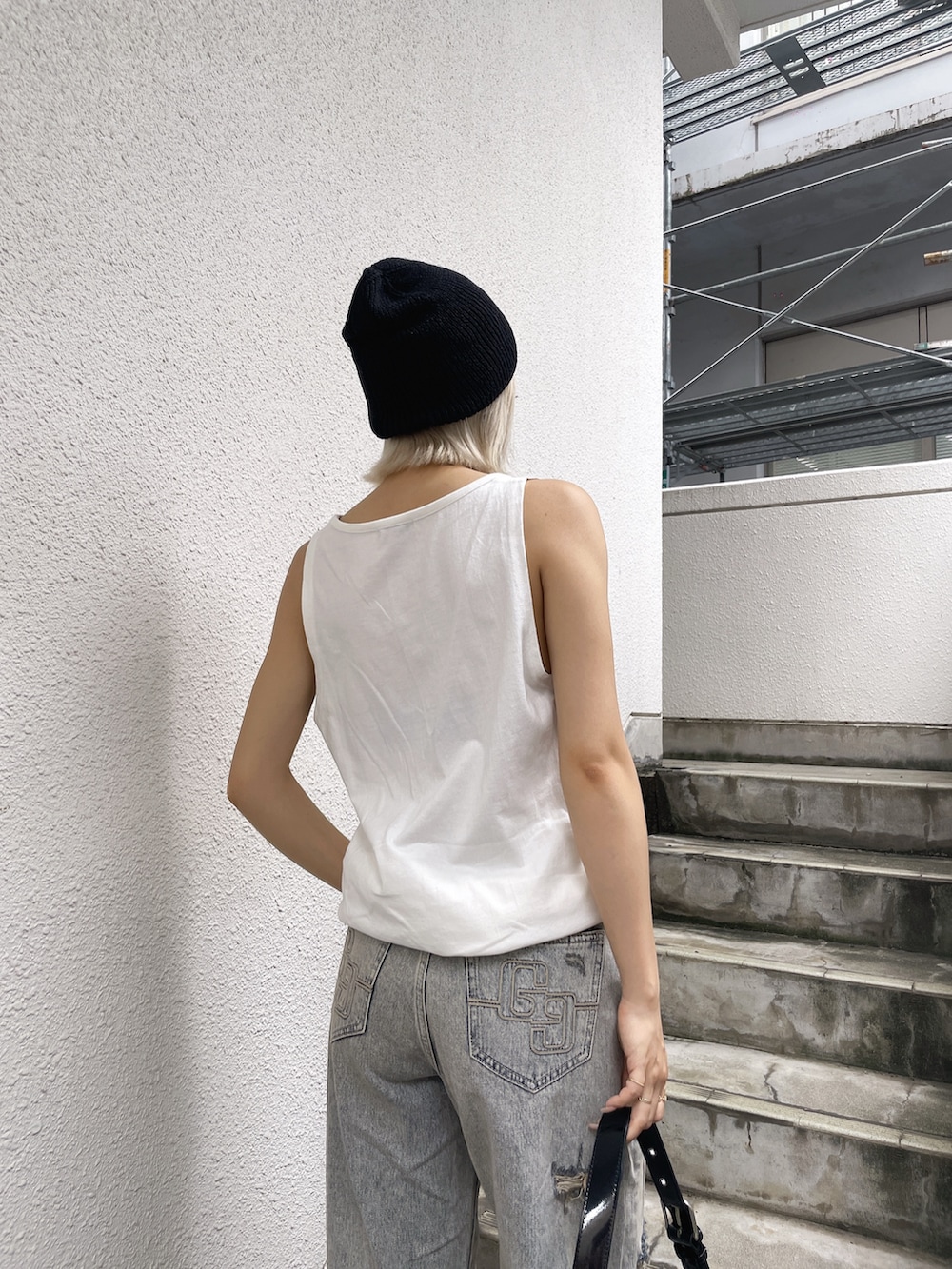 ホワイト系のワンピース、ブルー系のデニムパンツ、ブラック系のスニーカーを着用したレディースの夏コーディネートの3枚目の写真