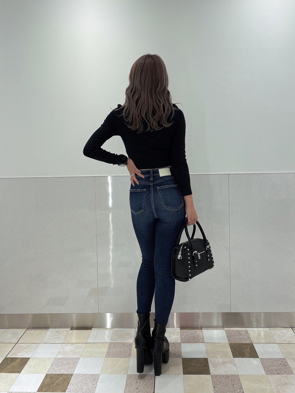 ブルー系のデニムパンツ、ブラック系のブーツ、ブラック系のボストンバッグを着用したレディースの秋コーディネートの2枚目の写真