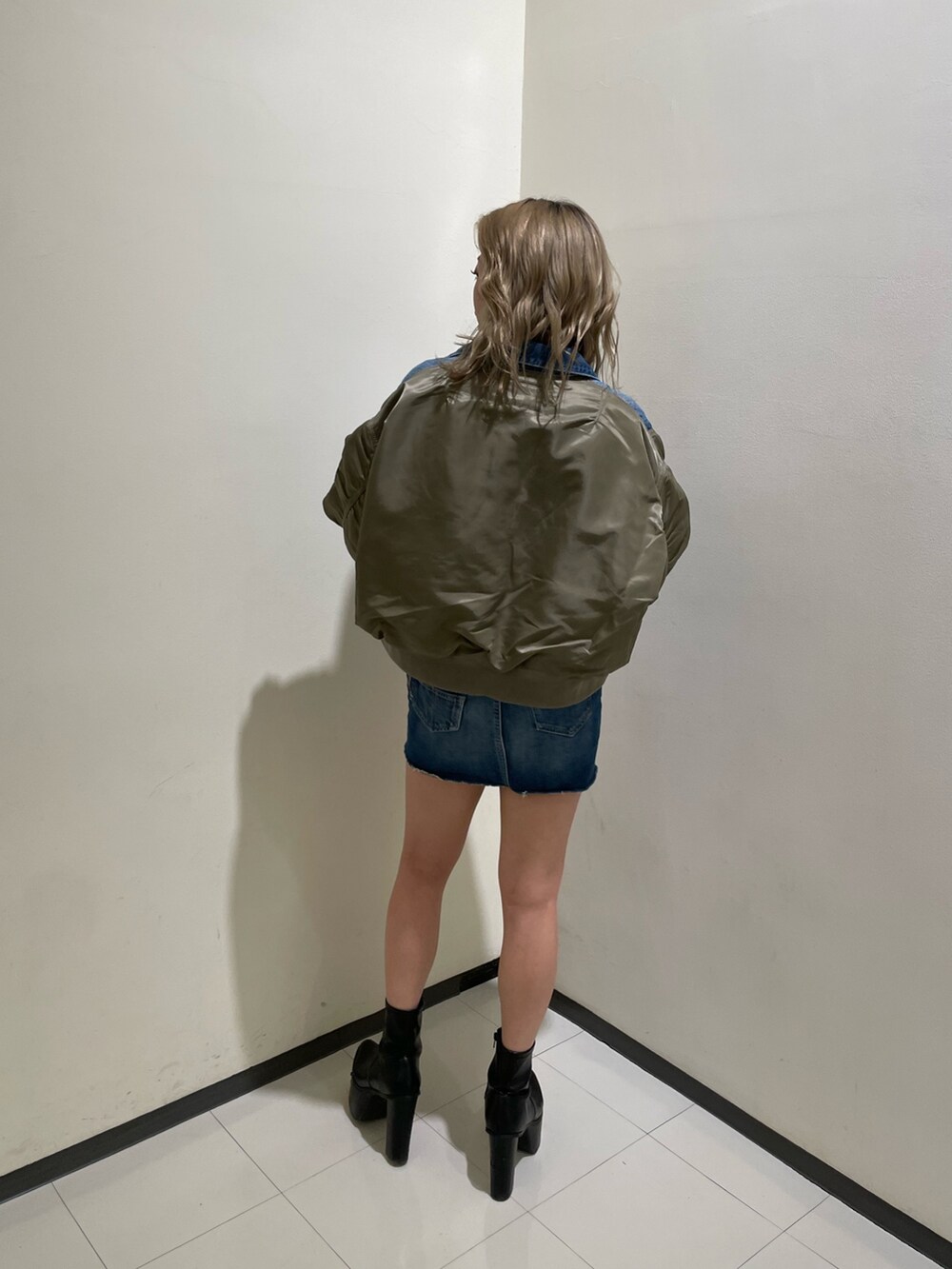 ブルー系のデニムスカート、ブラック系のブーツ、ブラック系のTシャツ/カットソーを着用したレディースの冬コーディネートの2枚目の写真