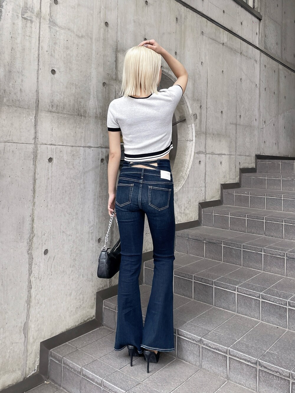 ホワイト系のニット/セーター、ブルー系のデニムパンツ、ブラック系のパンプスを着用したレディースの春コーディネートの3枚目の写真