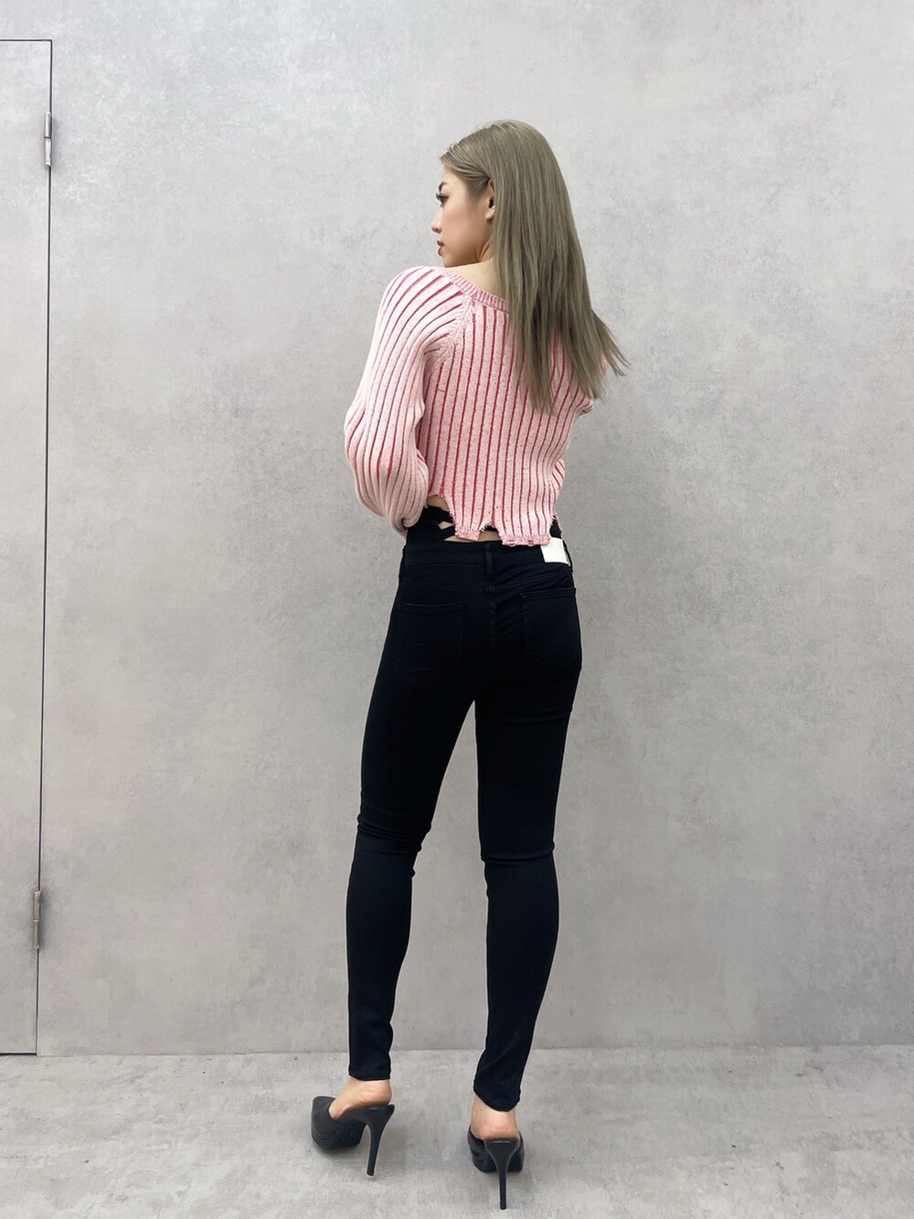 ピンク系のニット/セーター、ブラック系のデニムパンツ、ブラック系のパンプスを着用したレディースの冬コーディネートの2枚目の写真