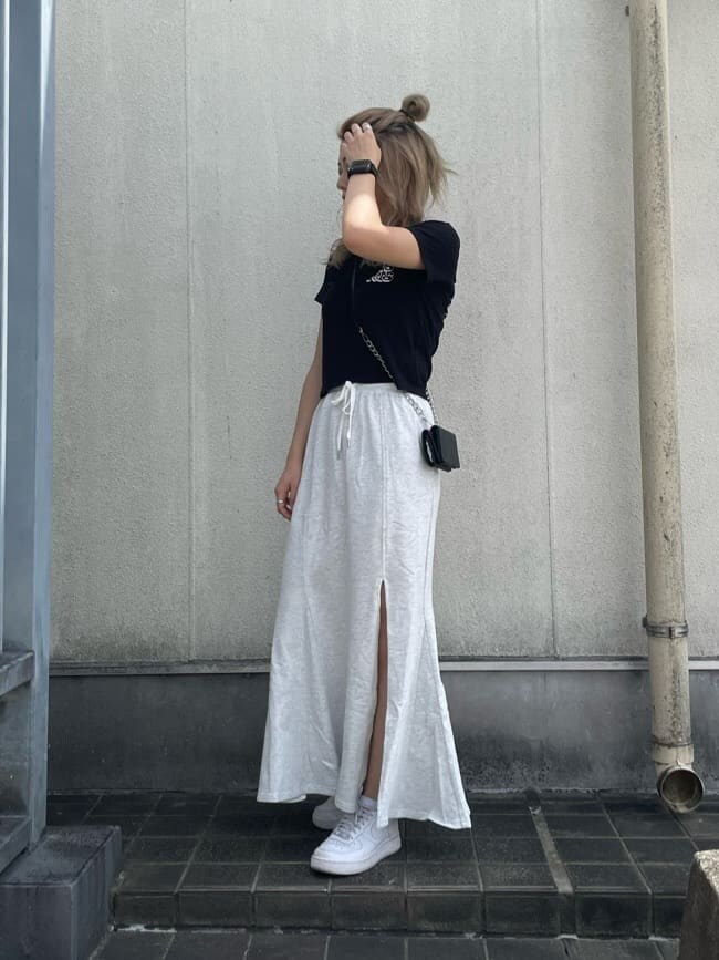 グレー系のスカート、ブラック系のTシャツ/カットソー、ブラック系の財布を着用したレディースの夏コーディネートの2枚目の写真