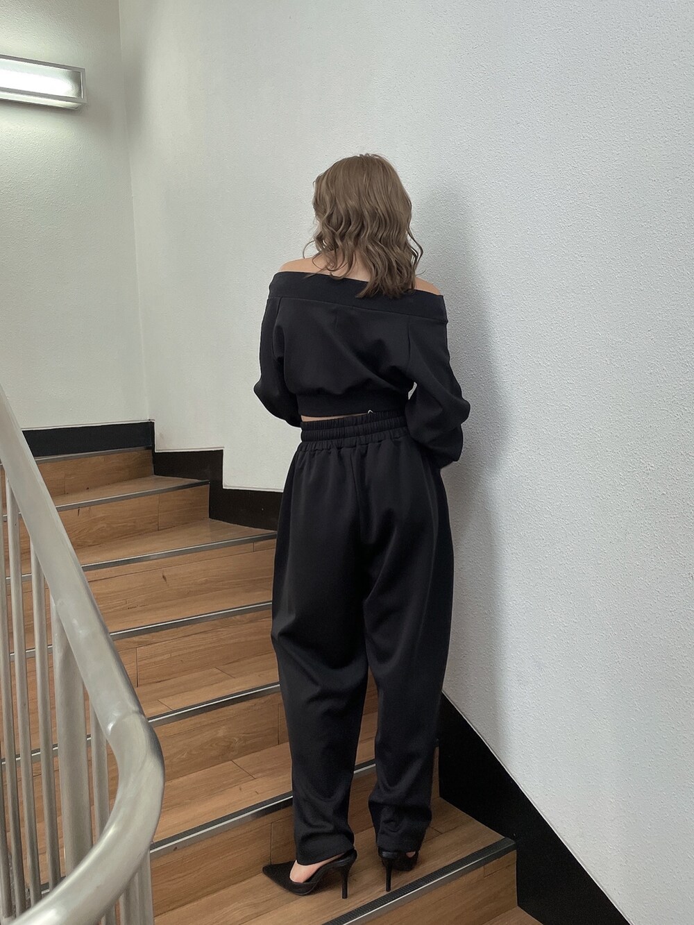 ブラック系のTシャツ/カットソー、ブラック系のスウェットパンツ、ブラック系のパンプスを着用したレディースの冬コーディネートの2枚目の写真
