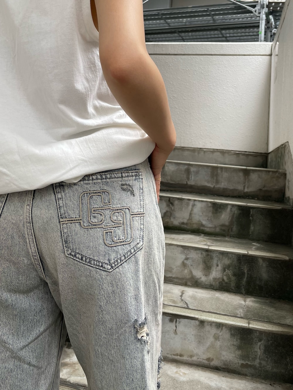 ホワイト系のワンピース、ブルー系のデニムパンツ、ブラック系のスニーカーを着用したレディースの夏コーディネートの4枚目の写真