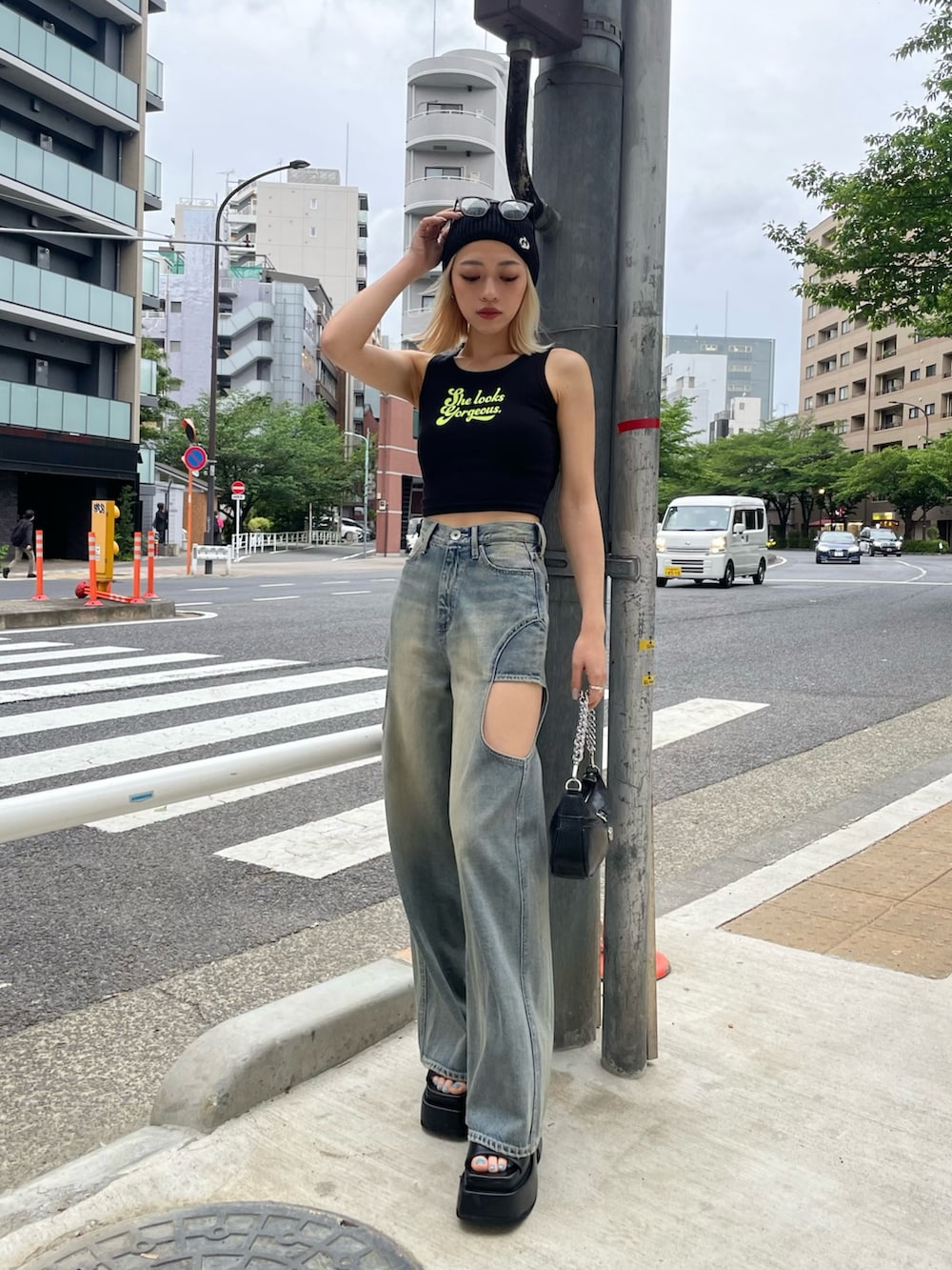 ブラック系のタンクトップ、ブルー系のデニムパンツ、ブラック系のハンドバッグを着用したレディースの春コーディネートの4枚目の写真