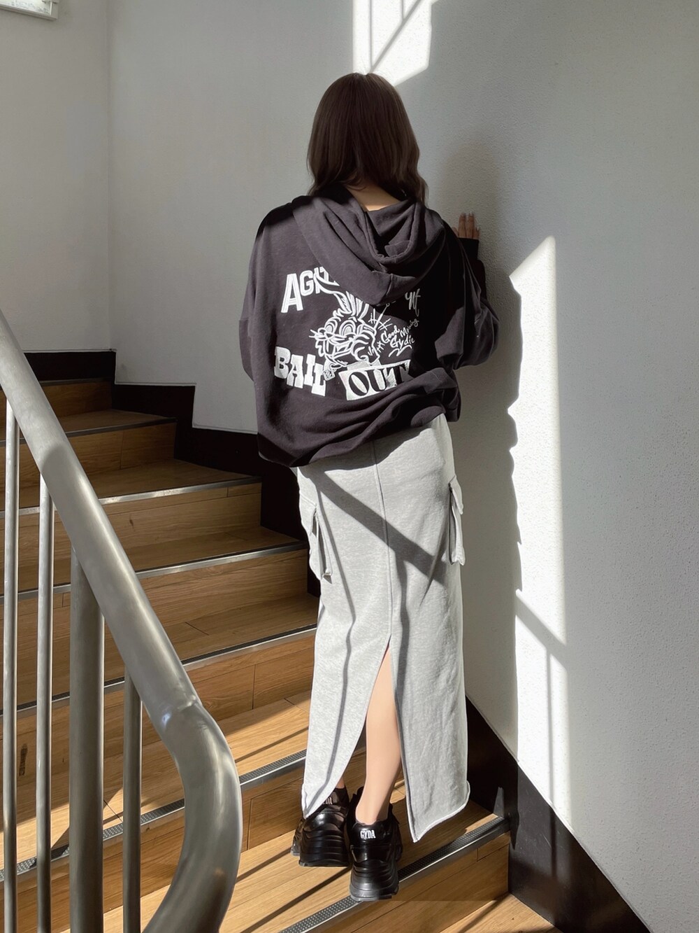 ブラック系のパーカー、グレー系のスカート、ブラック系のスニーカーを着用したレディースの冬コーディネートの2枚目の写真