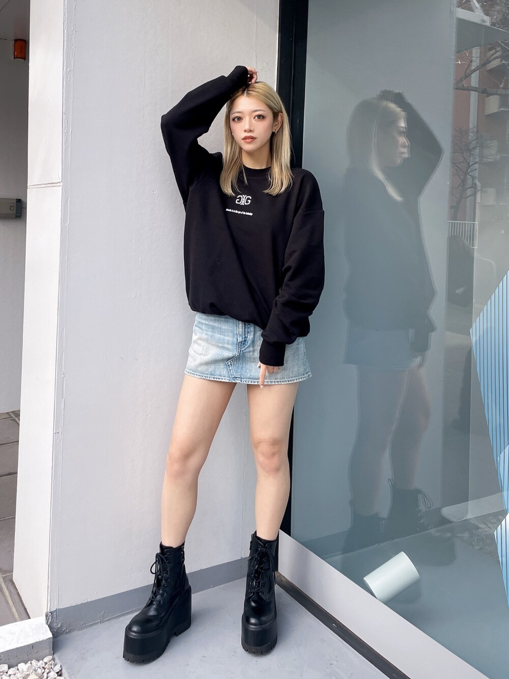 ブラック系のスウェット、ブルー系のデニムスカート、ブラック系のブーツを着用したレディースの冬コーディネートの2枚目の写真