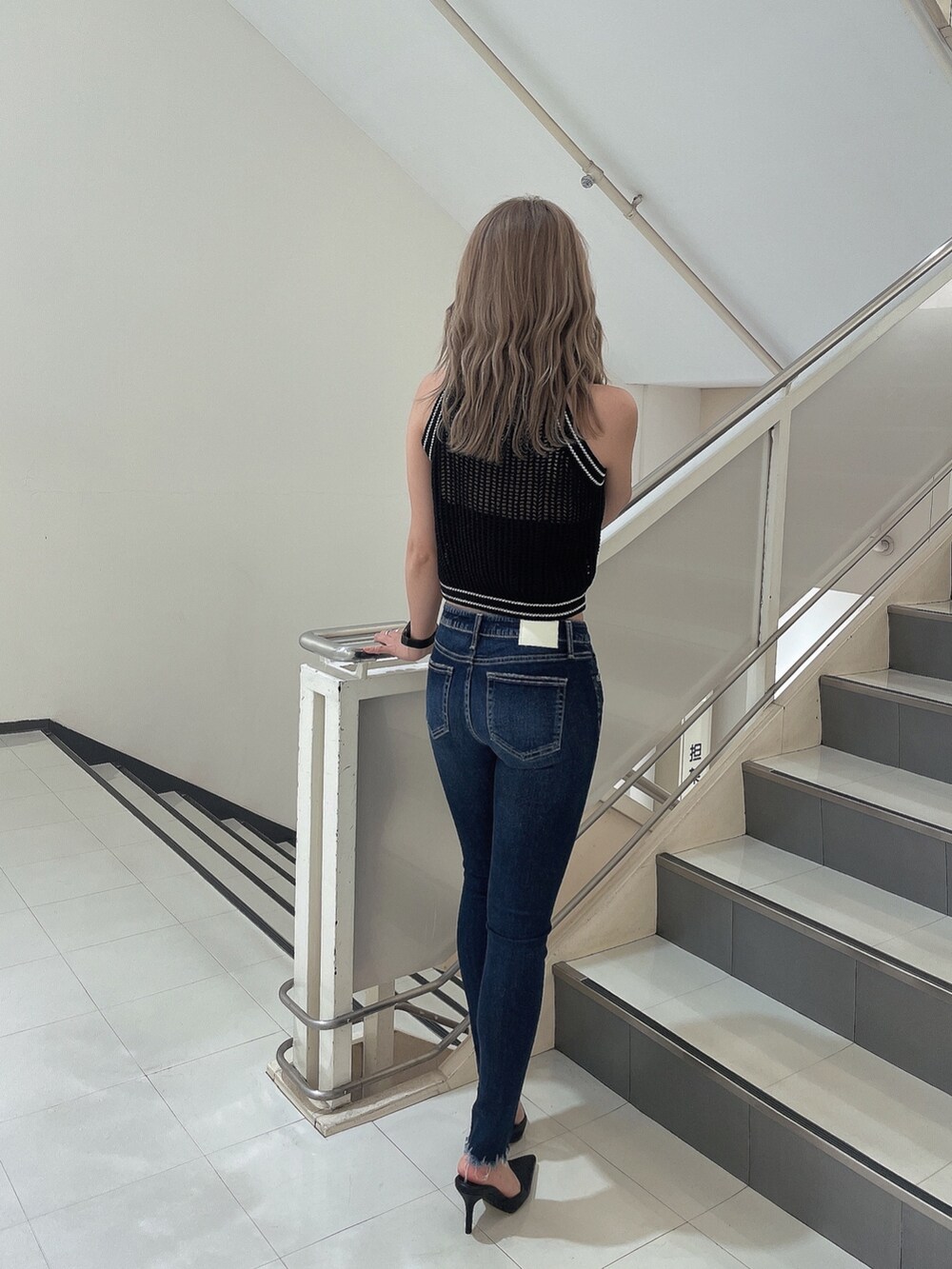 ブルー系のデニムパンツ、ブラック系のパンプス、ブラック系のニット/セーターを着用したレディースの夏コーディネートの3枚目の写真