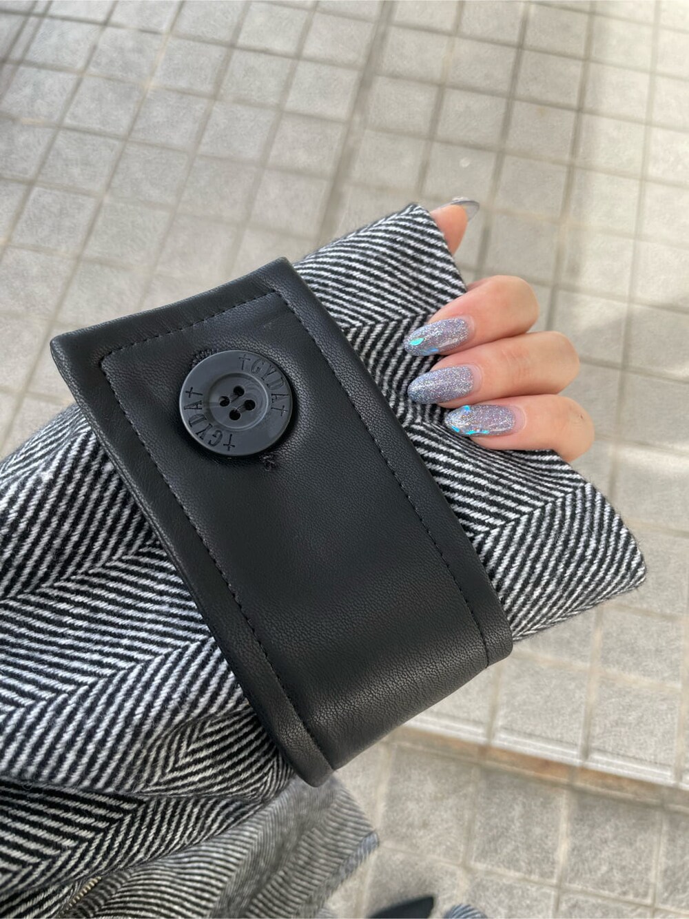 ブラック系のライダースジャケット、ホワイト系のニット/セーター、ブラック系のスカートを着用したレディースの秋コーディネートの7枚目の写真