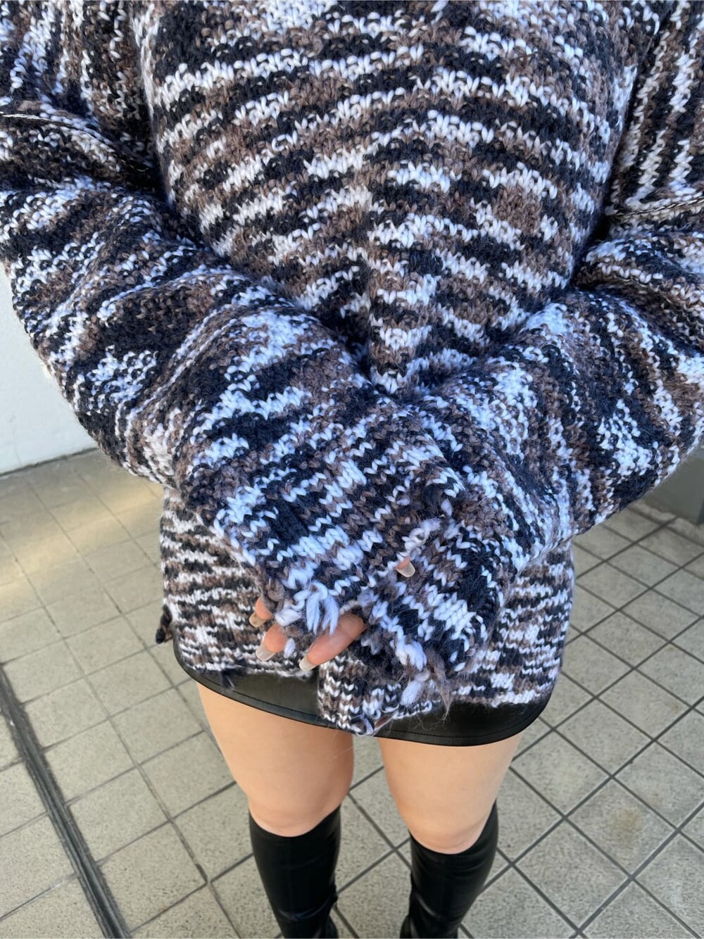 グレー系のニット/セーター、ブラック系のスカート、ブラック系のブーツを着用したレディースの秋コーディネートの6枚目の写真