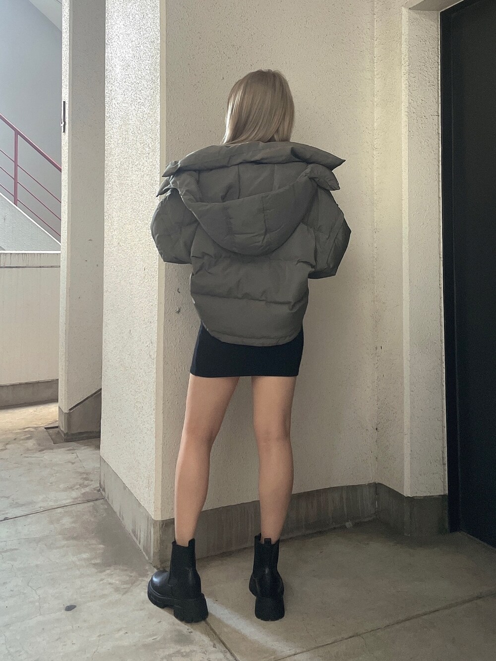 グリーン系のダウンジャケット/コート、ブラック系のワンピース、ブラック系のブーツを着用したレディースの秋コーディネートの2枚目の写真