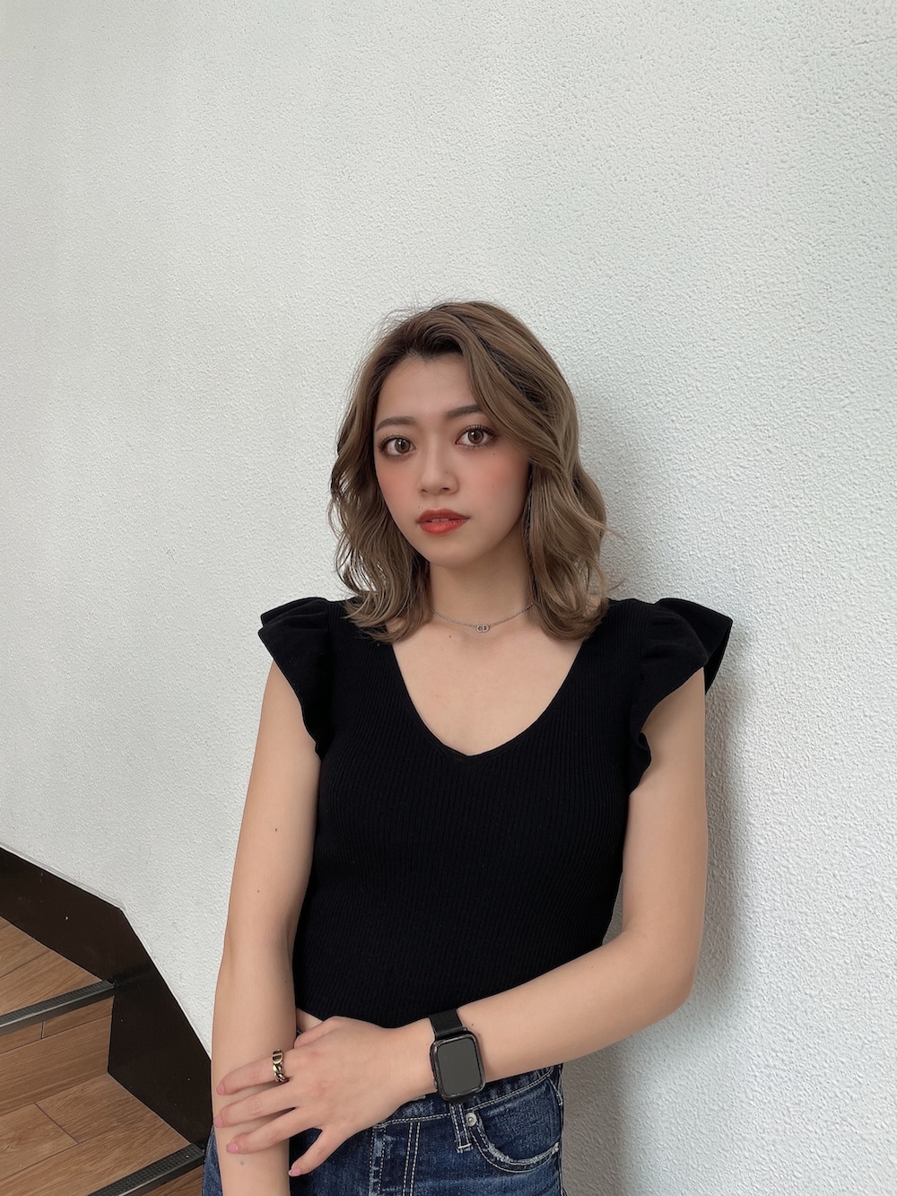 ブラック系のニット/セーター、ホワイト系のハンドバッグ、ブルー系のデニムパンツを着用したレディースの春コーディネートの4枚目の写真