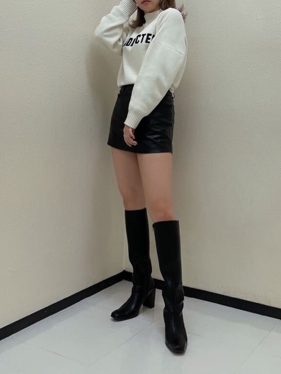ブラック系のスカート、ブラック系のブーツ、ホワイト系のニット/セーターを着用したレディースの秋コーディネートの3枚目の写真