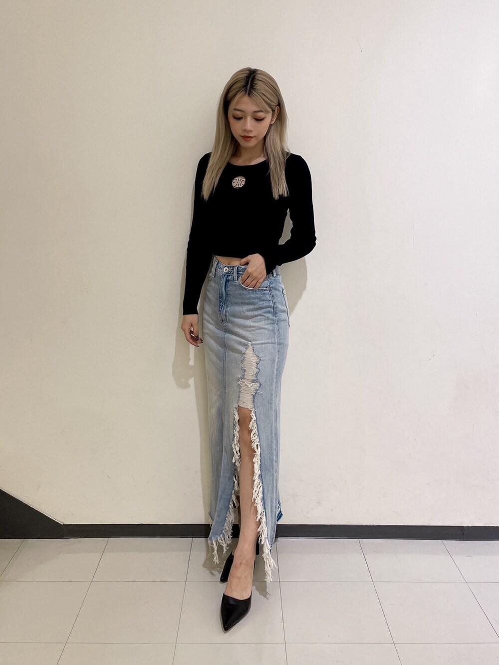 ブラック系のニット/セーター、ブルー系のデニムスカート、ブラック系のパンプスを着用したレディースの秋コーディネートの2枚目の写真