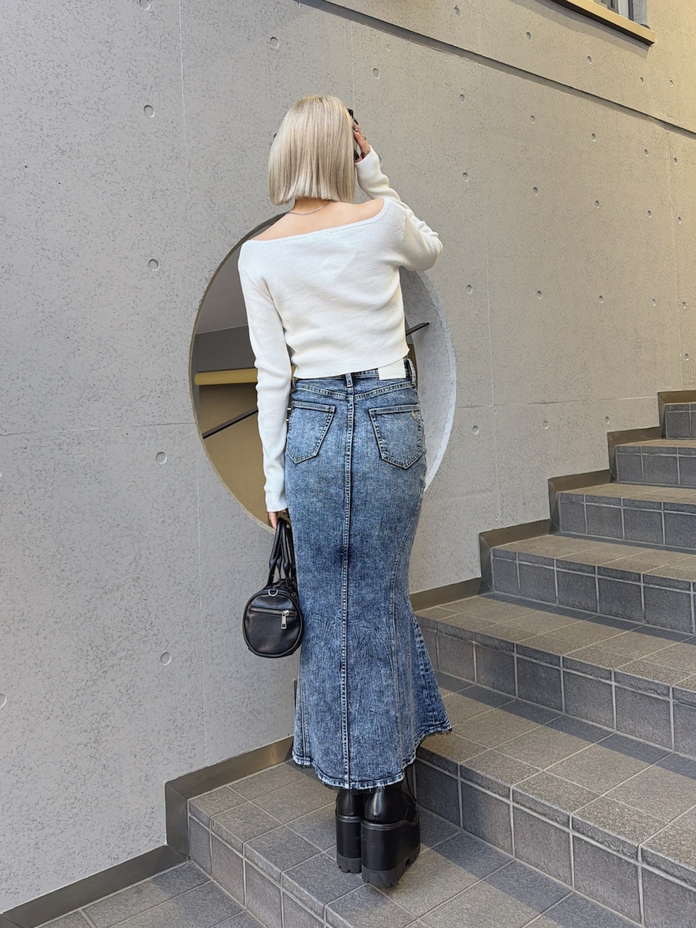 ブルー系のデニムスカート、ホワイト系のニット/セーターを着用したレディースの冬コーディネートの2枚目の写真