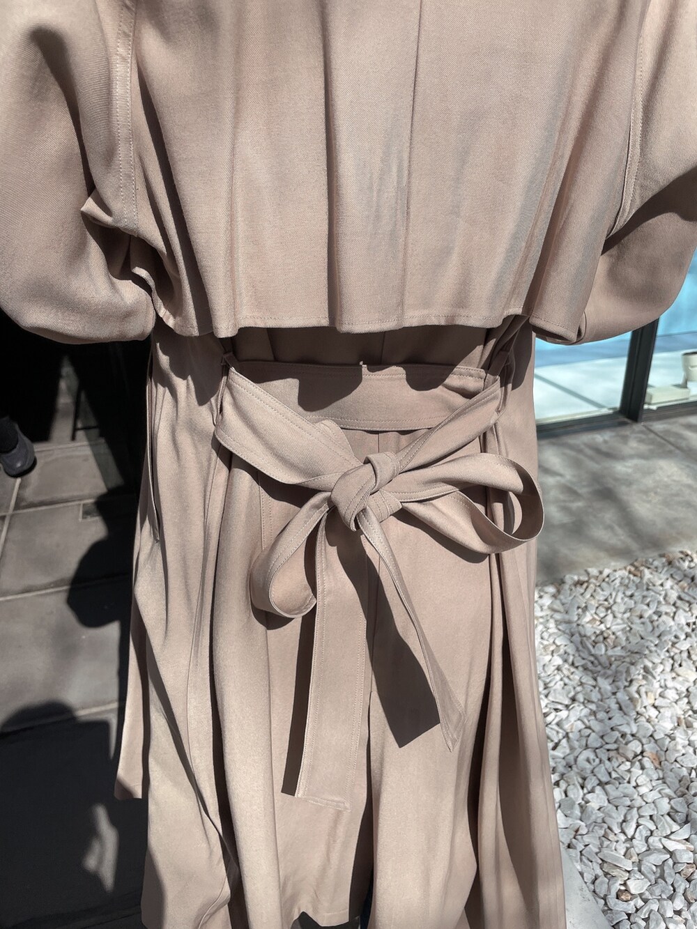 ホワイト系のニット/セーター、ベージュ系のトレンチコート、ブルー系のデニムパンツを着用したレディースの春コーディネートの6枚目の写真