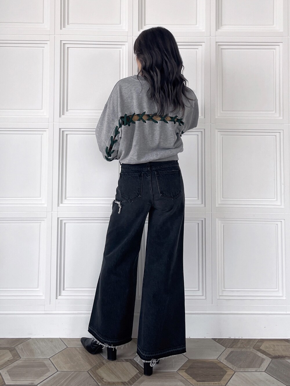 グレー系のスウェット、ブラック系のデニムパンツ、ブラック系のブーツを着用したレディースの秋コーディネートの2枚目の写真