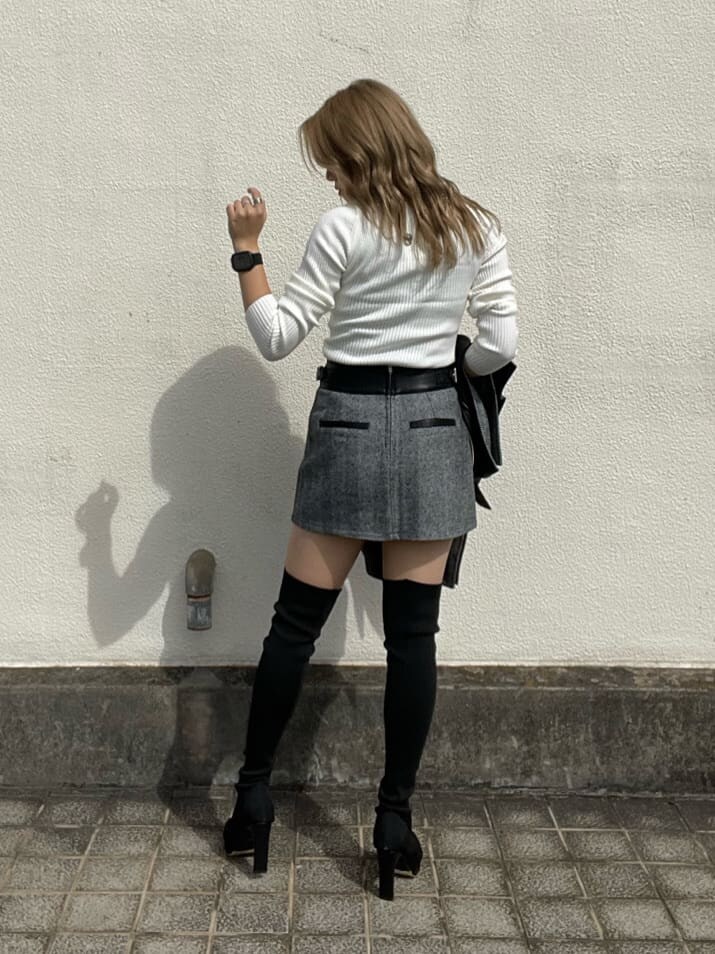 ブラック系のライダースジャケット、ホワイト系のニット/セーター、ブラック系のスカートを着用したレディースの秋コーディネートの6枚目の写真