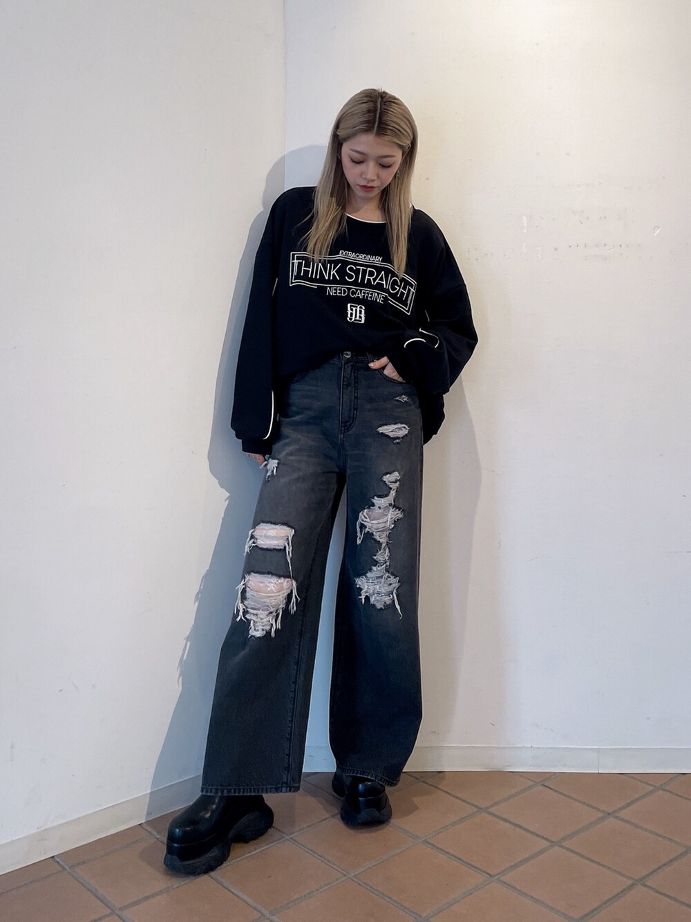 ブラック系のスウェット、ブラック系のデニムパンツ、ブラック系のブーツを着用したレディースの秋コーディネートの2枚目の写真