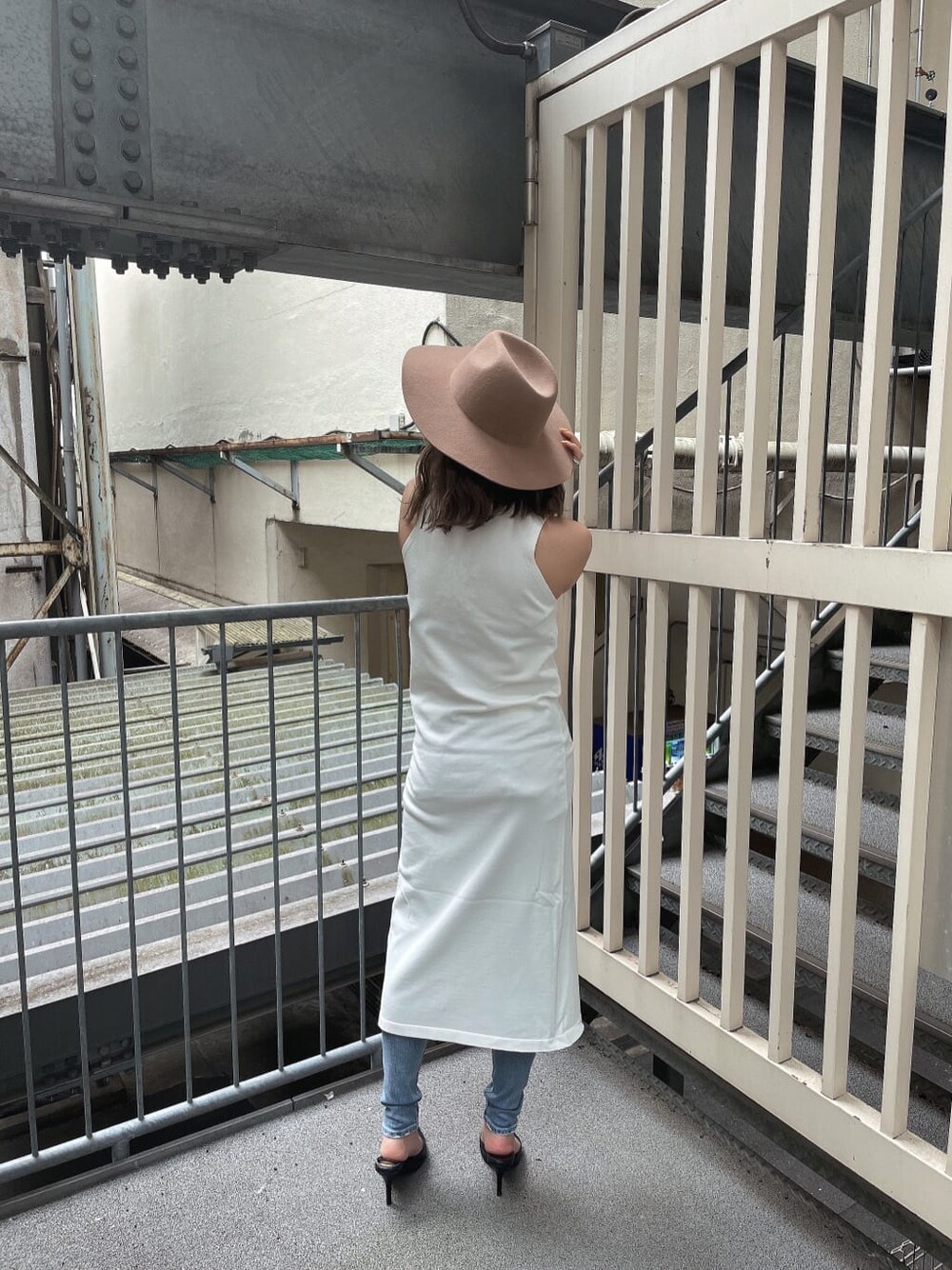 ホワイト系のニット/セーター、ブラック系のパンプス、ブルー系のデニムパンツを着用したレディースの夏コーディネートの4枚目の写真