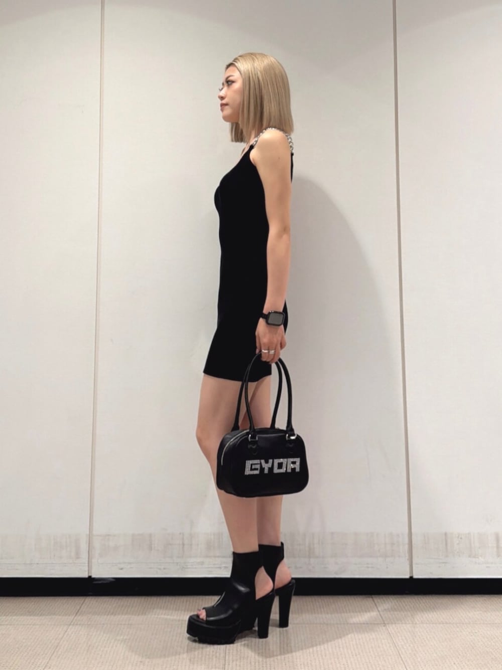 ブラック系のブーツ、ブラック系のボストンバッグ、ブラック系のワンピースを着用したレディースの夏コーディネートの2枚目の写真