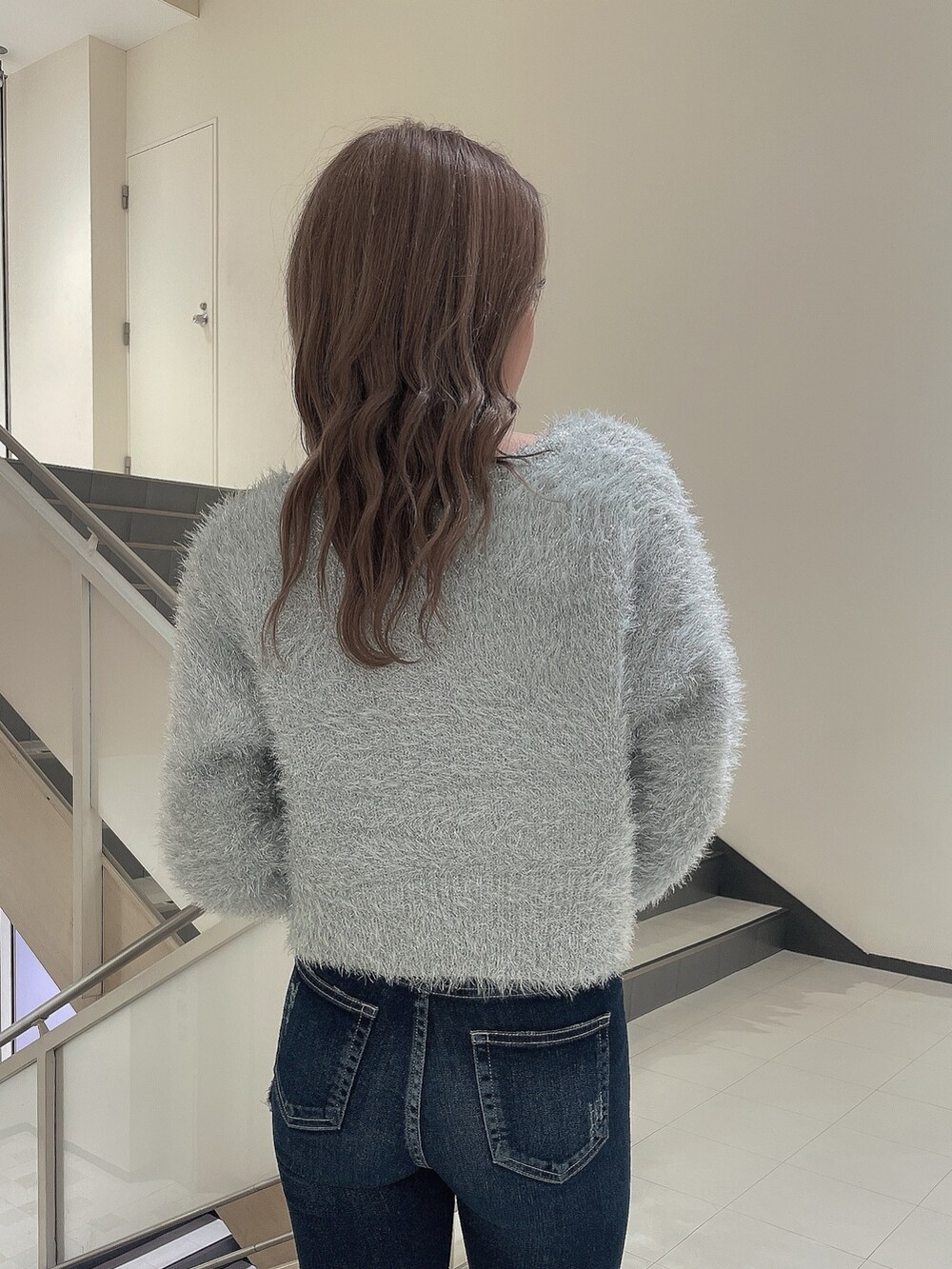 グレー系のニット/セーター、ブルー系のデニムパンツ、ホワイト系のパンプスを着用したレディースの冬コーディネートの6枚目の写真