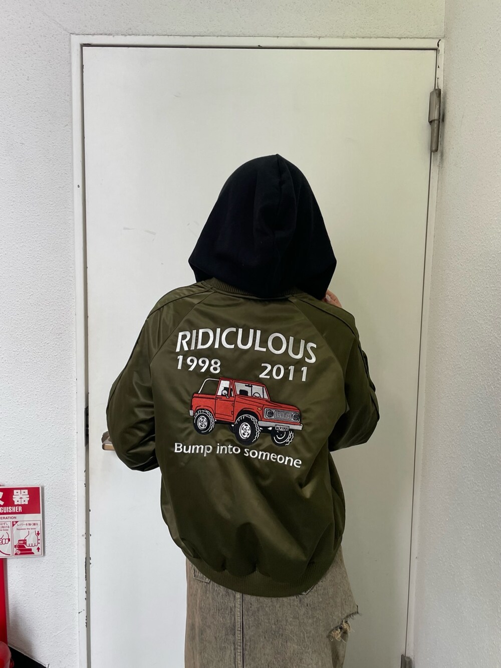 グリーン系のブルゾン、ブルー系のデニムスカート、ブラック系のブーツを着用したレディースの秋コーディネートの6枚目の写真