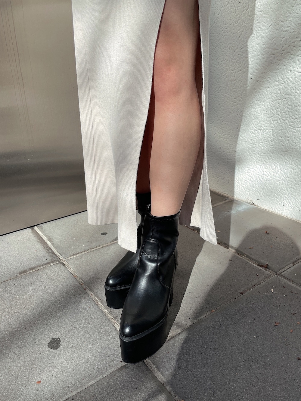 ホワイト系のニット/セーター、ホワイト系のスカート、ブラック系のブーツを着用したレディースの冬コーディネートの6枚目の写真