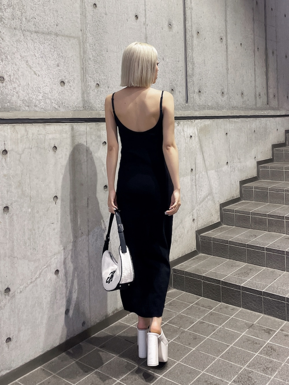 ホワイト系のハンドバッグ、ブラック系のワンピース、ホワイト系のサンダルを着用したレディースの夏コーディネートの2枚目の写真