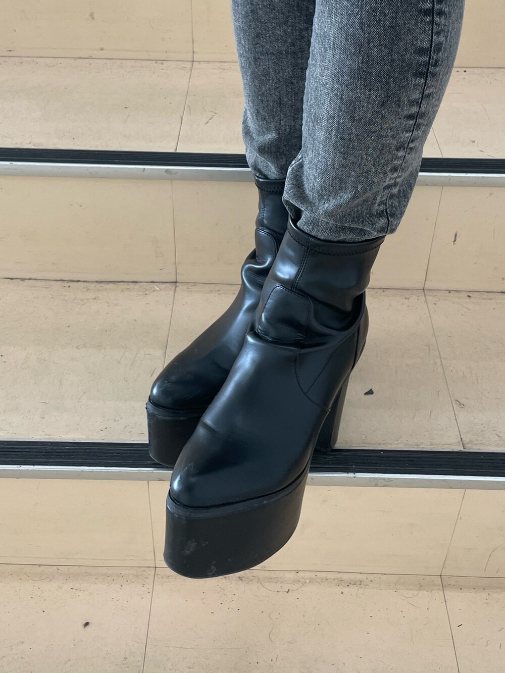 ブラック系のニット/セーター、ブラック系のデニムパンツ、ブラック系のブーツを着用したレディースの秋コーディネートの7枚目の写真