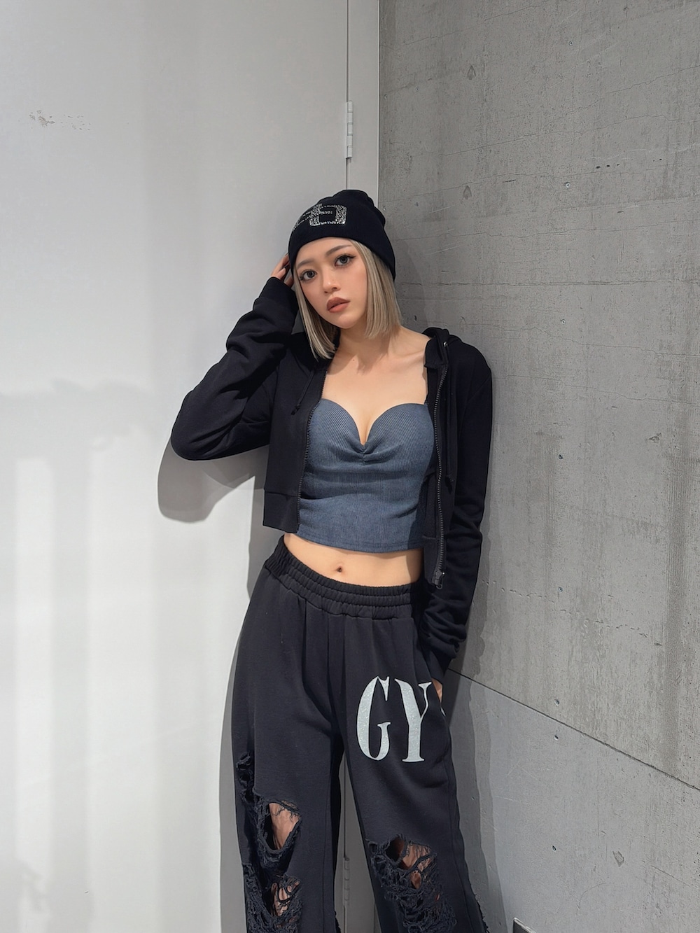 ブラック系のスウェットパンツ、ブラック系のパーカー、ブルー系のキャミソールを着用したレディースの春コーディネートの3枚目の写真