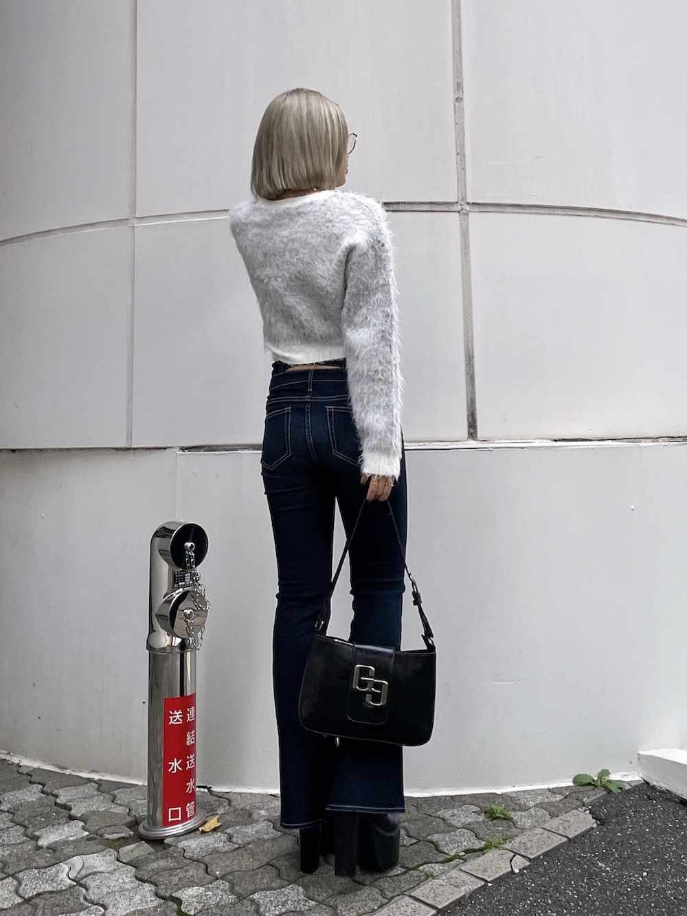 ホワイト系のニット/セーター、ブルー系のデニムパンツ、ブラック系のハンドバッグを着用したレディースの秋コーディネートの3枚目の写真