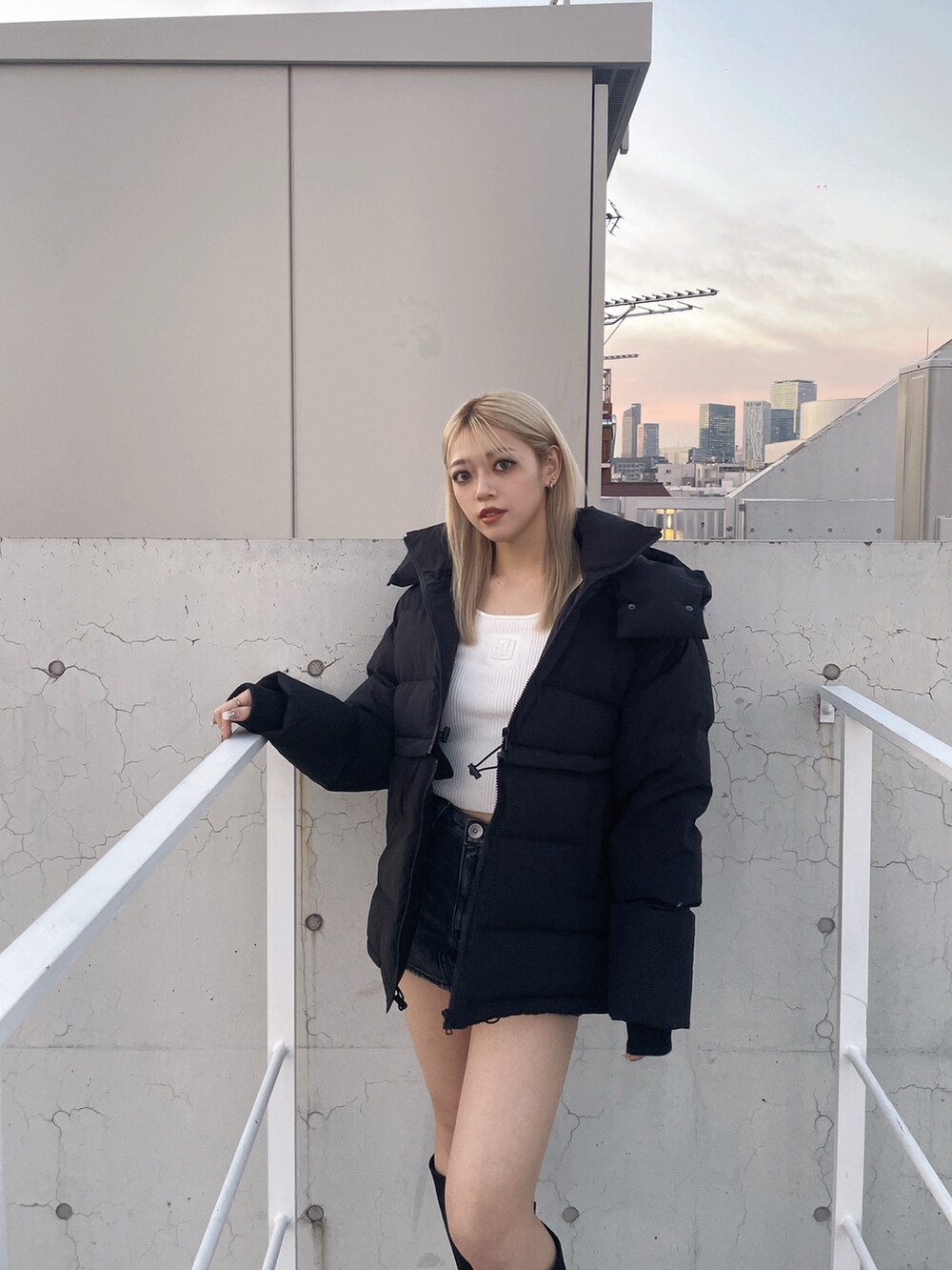 ブラック系のダウンジャケット/コート、ブラック系のデニムスカート、ホワイト系のニット/セーターを着用したレディースの冬コーディネートの4枚目の写真